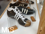 28.05.2026, Fussball DFB-Nationalmannschaft Deutschland. Im Hotel der Medienvertreter, dem Hotel HerzogsPark in Herzogenaurach, kann man gleich am Eingang in den Schaukästen etwas von der Historie des Hotels erfahren. Eng mit dem Namen Adi Dassler ist die Geschichte des Hotels HerzogsPark verbunden. Dort, wo noch
heute die Mannschaften der 1. Fußball Bundesliga logieren, gingen schon Ende der 60er Jahre weltberühmte Sportler ein und aus. Nach den Olympischen Spielen in München wurde aus dem eigens erbauten Gästehaus das Sporthotel adidas. 1992 kaufte
die Tochter Brigitte Baenkler-Dassler das Haus von der adidas AG und baute es zum Hotel HerzogsPark aus. Noch heute wird die Philosophie von Adi Dassler gelebt.  Im Schaukasten historische Adidas-Fussballschuhe aus den Jahren 1954 von der WM in der Schweiz und 1958. 