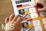 13.06.2026, Mindelheim (Bayern), das beliebte Sammelheft und die dazugehörigen Sammelbilder gibt es auch wieder zur Fussball-WM 2026 in den USA.  Ein Kind klebt Bildchen der deutschen Spieler ins Album ein. Hier Jonathan Tah (Deutschland) und Waldemar Anton (Deutschland) 