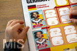 13.06.2026, Mindelheim (Bayern), das beliebte Sammelheft und die dazugehörigen Sammelbilder gibt es auch wieder zur Fussball-WM 2026 in den USA.  Ein Kind klebt Bildchen der deutschen Spieler ins Album ein. Hier Jonathan Tah (Deutschland) und Waldemar Anton (Deutschland) 