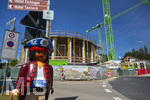 23.06.2026, Bad Wörishofen (Unterallgäu), Baustelle Löwenbräu-Arkaden Bad Wörishofen, der Neubau der Firma Glass aus Mindelheim kommt zügig voran, das Untergeschoss ist schon gut zu erkennen mit dem Rundbau und er Säulenarchitektur für die Terasse. Neben Wohnungen und Gastronomie und Tiefgaragen entsteht ein Ort der Begegnung im Herzen von Bad Wörishofen.  Links eine große Playmobilfigur vom nahen Spielwarengeschäft.
