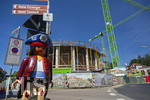 23.06.2026, Bad Wörishofen (Unterallgäu), Baustelle Löwenbräu-Arkaden Bad Wörishofen, der Neubau der Firma Glass aus Mindelheim kommt zügig voran, das Untergeschoss ist schon gut zu erkennen mit dem Rundbau und er Säulenarchitektur für die Terasse. Neben Wohnungen und Gastronomie und Tiefgaragen entsteht ein Ort der Begegnung im Herzen von Bad Wörishofen.  Links eine große Playmobilfigur vom nahen Spielwarengeschäft.
