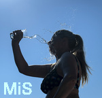 24.06.2026, Sommerhitze in Deutschland, Mindelheim im Unterallgäu, eine Frau erfrischt sich mit einem schwall kaltem Wasser in ihr Gesicht. (Modelrelased)  