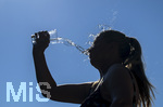24.06.2026, Sommerhitze in Deutschland, Mindelheim im Unterallgäu, eine Frau erfrischt sich mit einem schwall kaltem Wasser in ihr Gesicht. (Modelrelased)  