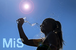 BILDBEARBEITUNG! 24.06.2026, Sommerhitze in Deutschland, Mindelheim im Unterallgäu, eine Frau erfrischt sich mit einem schwall kaltem Wasser in ihr Gesicht. (Modelrelased)  