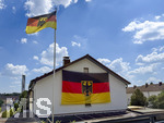 26.06.2026, Fussball WM 2026, Stimmungs-Bilder aus Deutschland. An einem Wohnhaus in Kaufbeuren (Bayern) hängt eine riesige Deutschlandfahne an der Hauswand und am Fahnenmast auch eine Deutsche Landesflagge.