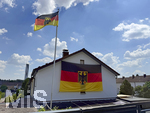 26.06.2026, Fussball WM 2026, Stimmungs-Bilder aus Deutschland. An einem Wohnhaus in Kaufbeuren (Bayern) hängt eine riesige Deutschlandfahne an der Hauswand und am Fahnenmast auch eine Deutsche Landesflagge. 