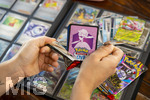 05.08.2026, Deutschland, Bayern, Pokemon-Sammelkarten, eine Teenagerin sammelt begeistert Pokemon-Karten für ihr Sammelheft, eine neue Packung mit Karten wird ausgepackt,