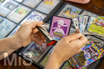 05.08.2026, Deutschland, Bayern, Pokemon-Sammelkarten, eine Teenagerin sammelt begeistert Pokemon-Karten für ihr Sammelheft, eine neue Packung mit Karten wird ausgepackt,