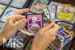 05.08.2026, Deutschland, Bayern, Pokemon-Sammelkarten, eine Teenagerin sammelt begeistert Pokemon-Karten für ihr Sammelheft, eine neue Packung mit Karten wird ausgepackt,