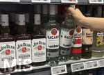 05.08.2026, Deutschland, Bayern, Spirituosen im Angebot der Getränkeabteilung eines Supermarktes in Bayern, ein junges Mädchen (Teenager) greift nach einer Bacardy-Rum-Flasche