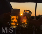 11.08.2026, Bad Wörishofen im Unterallgäu, Sonnenuntergangsstimmung in einem Biergarten am Ortsrand der Kneippstadt. Zwei Gäste prosten sich zu mit Bierkrügen. Am Mittwoch ist Sonnenfinsternis (12.08.2026), da ist dieser Punkt optimal für die Beobachtung des Himmelsereignisses.