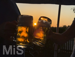 11.08.2026, Bad Wörishofen im Unterallgäu, Sonnenuntergangsstimmung in einem Biergarten am Ortsrand der Kneippstadt. Zwei Gäste prosten sich zu mit Bierkrügen. Am Mittwoch ist Sonnenfinsternis (12.08.2026), da ist dieser Punkt optimal für die Beobachtung des Himmelsereignisses.