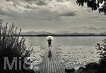 20.08.2026, am Hopfensee bei Füssen im Allgäu, Ein Steg führt in den See, hinten zieht ein Gewitter auf wo der Regen bereits aus den Wolken fällt. Eine Frau steht mit Regenschirm am Ende des Steges. (Modelreleased)