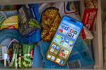 23.08.2026, Handys in der Sommerhitze, das Handy ist überhitzt und muss gekühlt werden. Hier im Gefrierfach vom Kühlschrank, das ist nicht empfehlenswert, wegen Schäden im Handy durch Kondenswasser.