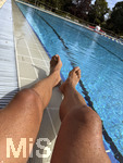 04.09.2026, Freibad Bad Wörishofen (Bayern), ein Mann sitzt am Schwimmbecken und lässt seine Beine bräunen.  (Model Release vorhanden)   