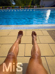 04.09.2026, Freibad Bad Wörishofen (Bayern), ein Mann sitzt am Schwimmbecken und lässt seine Beine bräunen.  (Model Release vorhanden)   