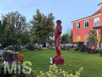 07.09.2026, Kurtheater Bad Wörishofen, Der Platz vor dem Kurhaus und der Kurmuschel. Derzeit findet der Kunstsommer statt, hier steht ein nackter rotlackierter Holz-Mann im Rasen eines teilnehmenden Künstlers. An dieser Stelle auf dem Rasen soll bald ein über 30 m hohes Riesenrad stehen, als neue Attraktion für die Kurstadt.  Beim Freiluftkonzert der Band Rock Fun sitzen die Besucher sogar hinter dem Blumenbeet.