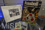 01.10.2026, Fussball UEFA Nations-League 2026/2027, 3.Spieltag, Deutschland - Serbien, in der Allianz-Arena München. Im Presseraum liegen alte Nationalmannschafts-Devotionalien in einer Vitrine, Ein Fussball-Buch und ein Foto links von Torjäger Gerd Müller 